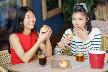 Joyful Asian women eating delicious food during lunch together