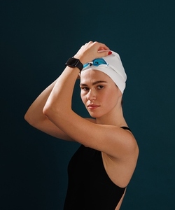 Portrait of a young professional female swimmer looking at the camera against blue background
