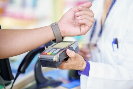 Man paying by smartwatch with dataphone in a pharmacy