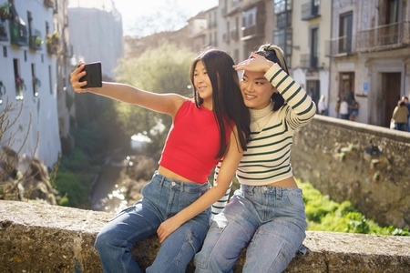 Joyful young Asian women taking self portrait on bridge
