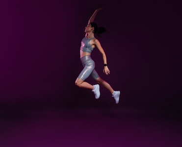 Full length of young female athlete jumping in the air over magenta background