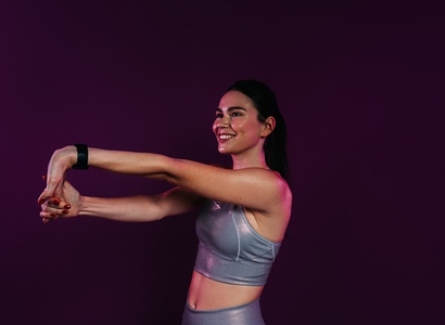 Smiling female stretching and flexing her hands over magenta background in studio