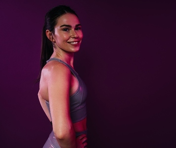 Side view of a healthy smiling female over magenta background in studio