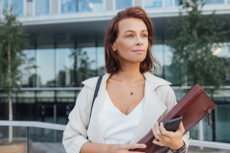 Middle aged businesswoman outdoors  Female in formal wear and a leather folder looking away