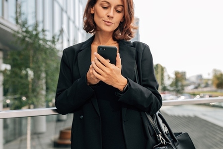 Close up of a middle aged businesswoman in formal clothes using a mobile phone