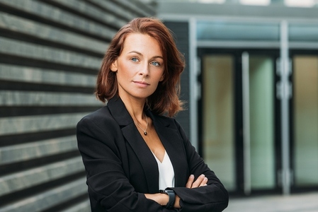 Portrait of a confident businesswoman with ginger hair  Middle aged businesswoman standing with crossed arms outdoors