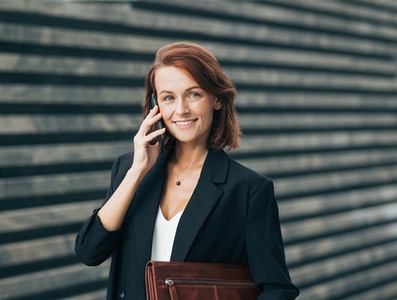 Smiling middle aged businesswoman making a phone call and looking at the camera