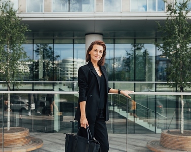 Side view of a confident middle aged businesswoman with a bag standing against an office building