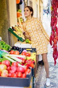 Smiling young woman posing stylishly with fruits and vegetables in shop