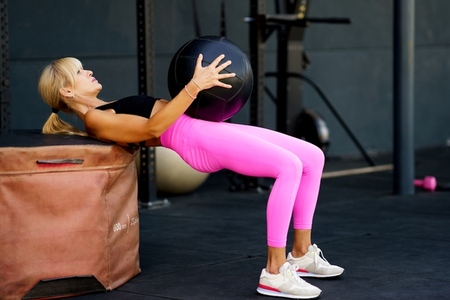 Determined female exercising with ball in fitness gym