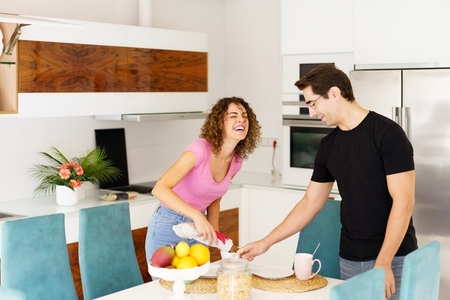 Happy couple standing near dining table and having fun