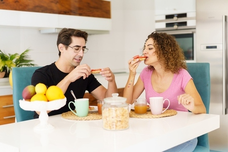 Happy adult couple sitting at dining table and speaking during breakfast