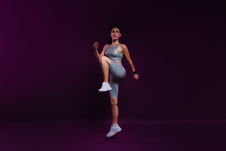 Full length of a slim female warming up her body against a magenta backdrop in the studio