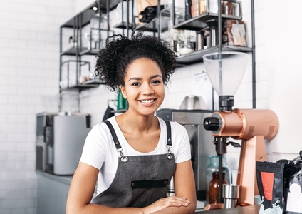 Portrait of a smiling barista with curly hair  Young female working as a barista in a coffee shop