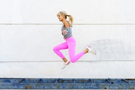 Happy active woman jumping above ground on street