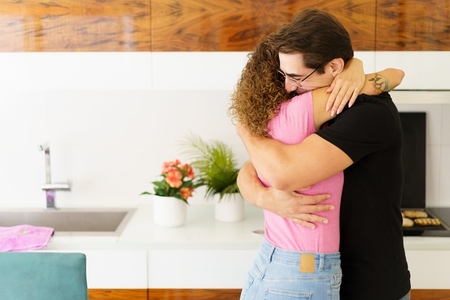 Happy couple standing in kitchen and hugging each other in daylight