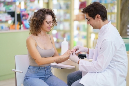 Male doctor checking blood sugar level of patient sitting in pharmacy