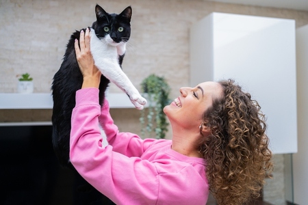 Happy young woman spending time playing with cute cat