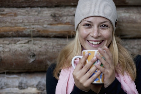 Smiling young woman holding a mug in her hands