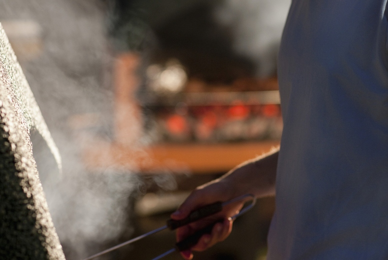 Young man standing at barbeque holding tongs