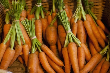 Close up of a basket filled with trimmed bunches of carrots