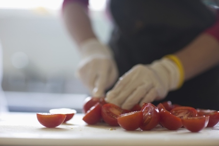 Close up of a worker hands cutting fresh tomatoes
