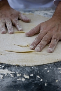 Close up of a chef hands covered in flour kneading a pizza dough