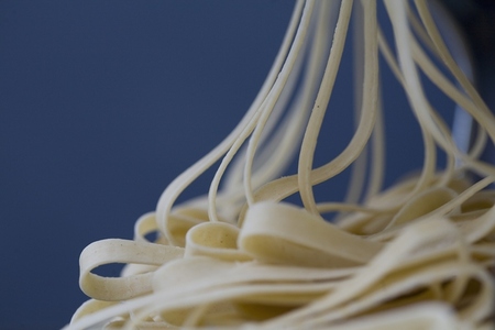 Heap of fresh tagliatelle coming out of a pasta maker