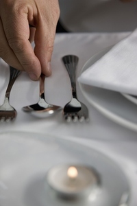 Close up of a waiter hand arranging cutlery on a restaurant table