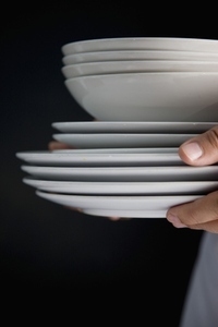 Close up of waiter hands carrying a stack of plates and bowls