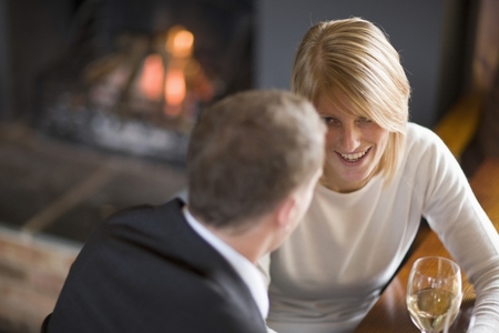 Couple sitting by a fireplace drinking wine