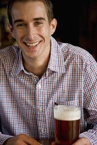 Smiling man sitting and holding a pint of beer