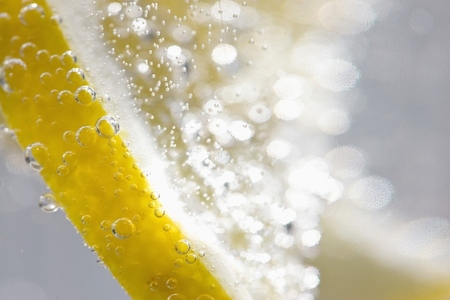 Extreme close up of a slice of lemon floating in sparkling water