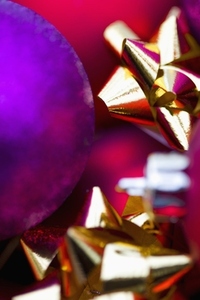 Extreme close up of red and purple Christmas baubles and gold bows