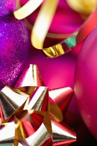 Extreme close up of red and purple Christmas baubles and a gold bow and ribbon