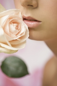 Extreme close up of a young woman inhaling a pink rose