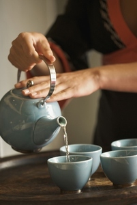 Close up of a woman hands pouring green tea