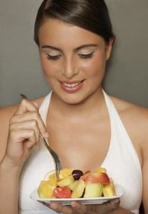Smiling young woman eating a fruit salad