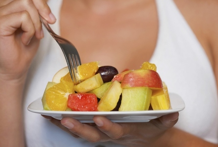 Close up of a young woman holding a bowl of fruit salad