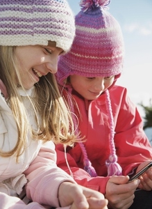 Two young girls wearing woolly hats and holding a mp3 player
