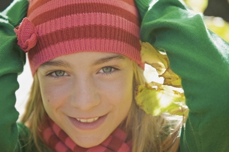 Smiling young girl with her hands on her head wearing a woolly hat