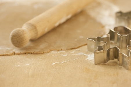 Close up of rolled out pastry dough with wooden rolling pin and cookie cutters