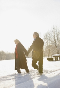 Mature couple walking in the snow holding hands