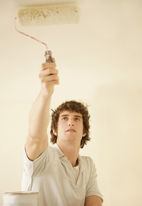 Portrait of a man painting the ceiling with a paint roller