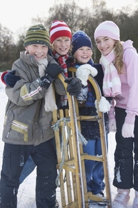 Smiling children leaning on a sled