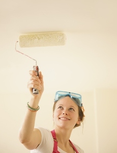 Portrait of a woman painting the ceiling with a paint roller
