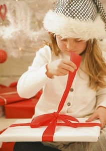 Girl in a furry hat unwrapping a Christmas gift