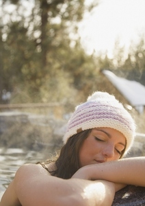 Young woman resting on the edge of a hot tub with her eyes closed