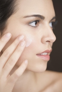 Close up of a woman applying moisturiser on her face