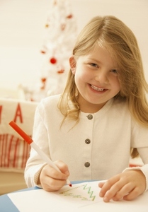 Smiling girl writing a letter to Father Christmas